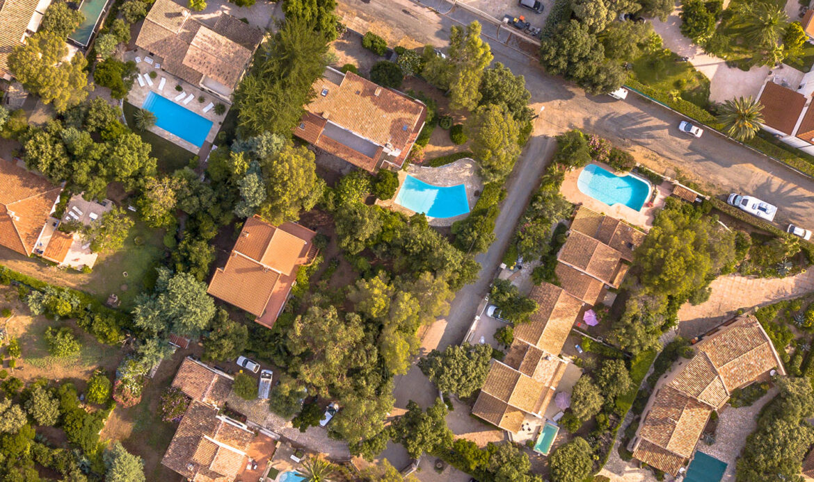 Vue aérienne d'un quartier résidentiel méditerranéen, avec des villas entourées de végétation et des piscines, idéal pour des observations discrètes et des enquêtes sur le terrain.